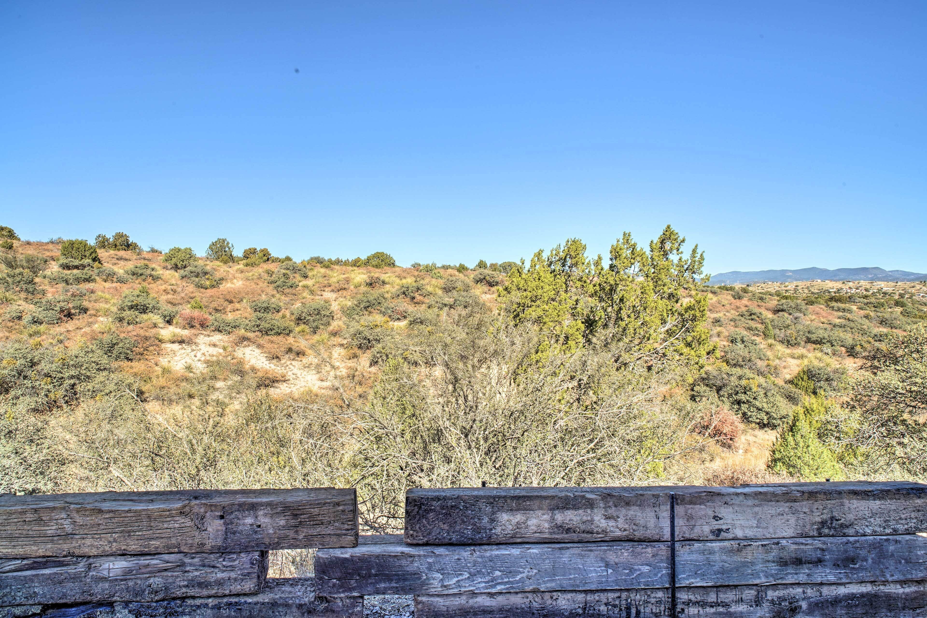 A wooden bench overlooking a hilly landscape with sparse vegetation and distant mountains.
