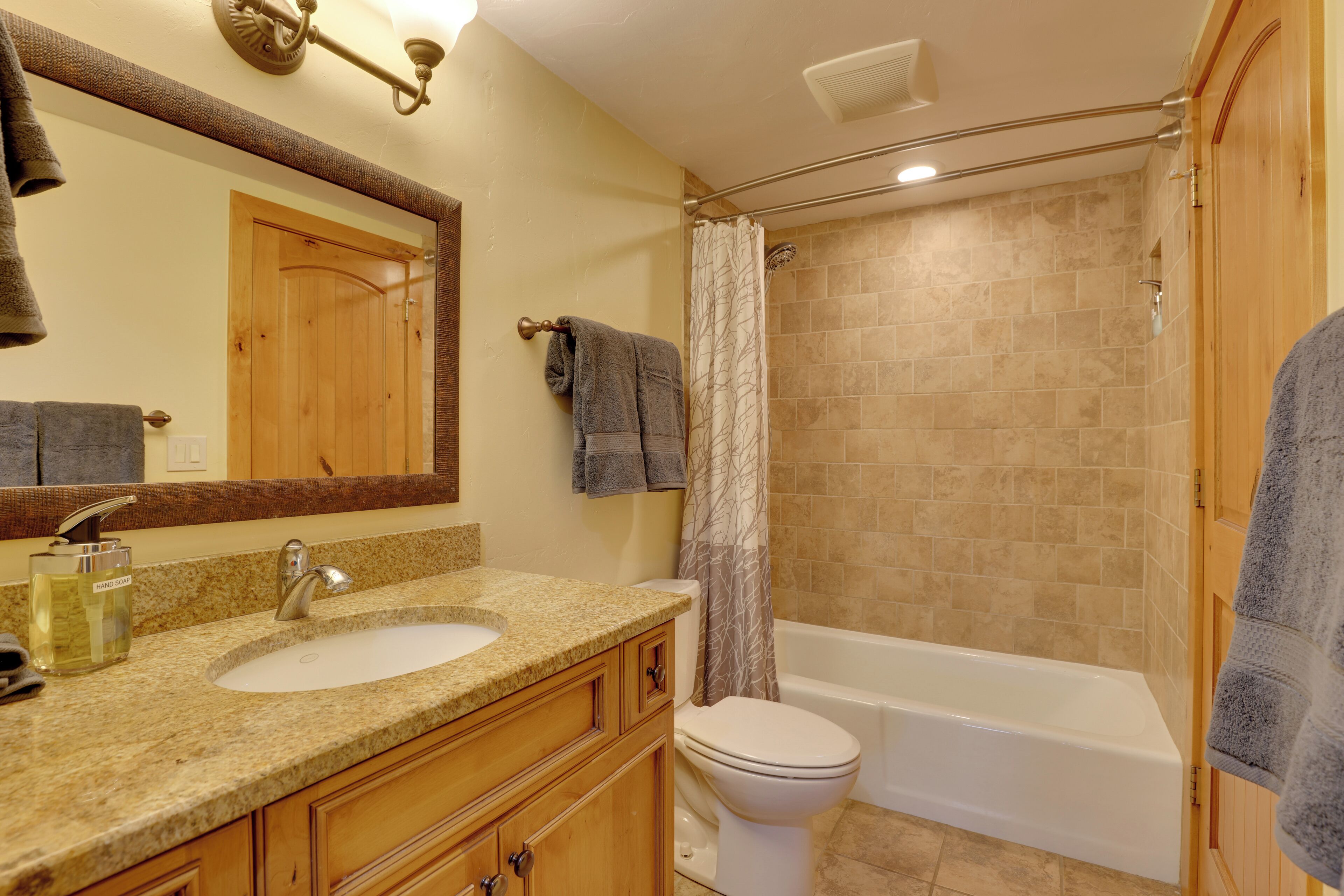 A bathroom with a sink, mirror, toilet, and bathtub.