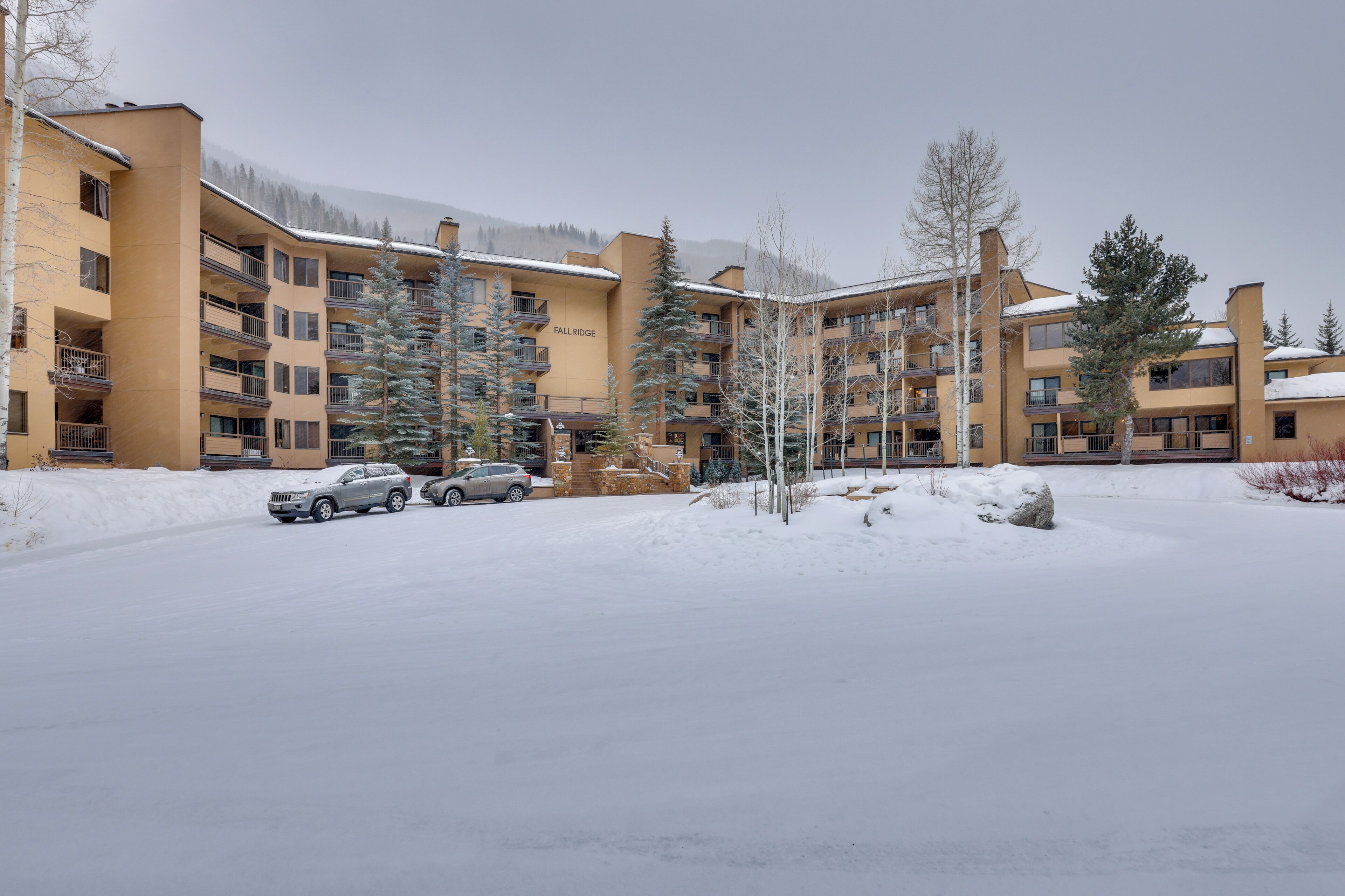 A multi-story hotel with balconies, a parking area, and snow-covered surroundings.