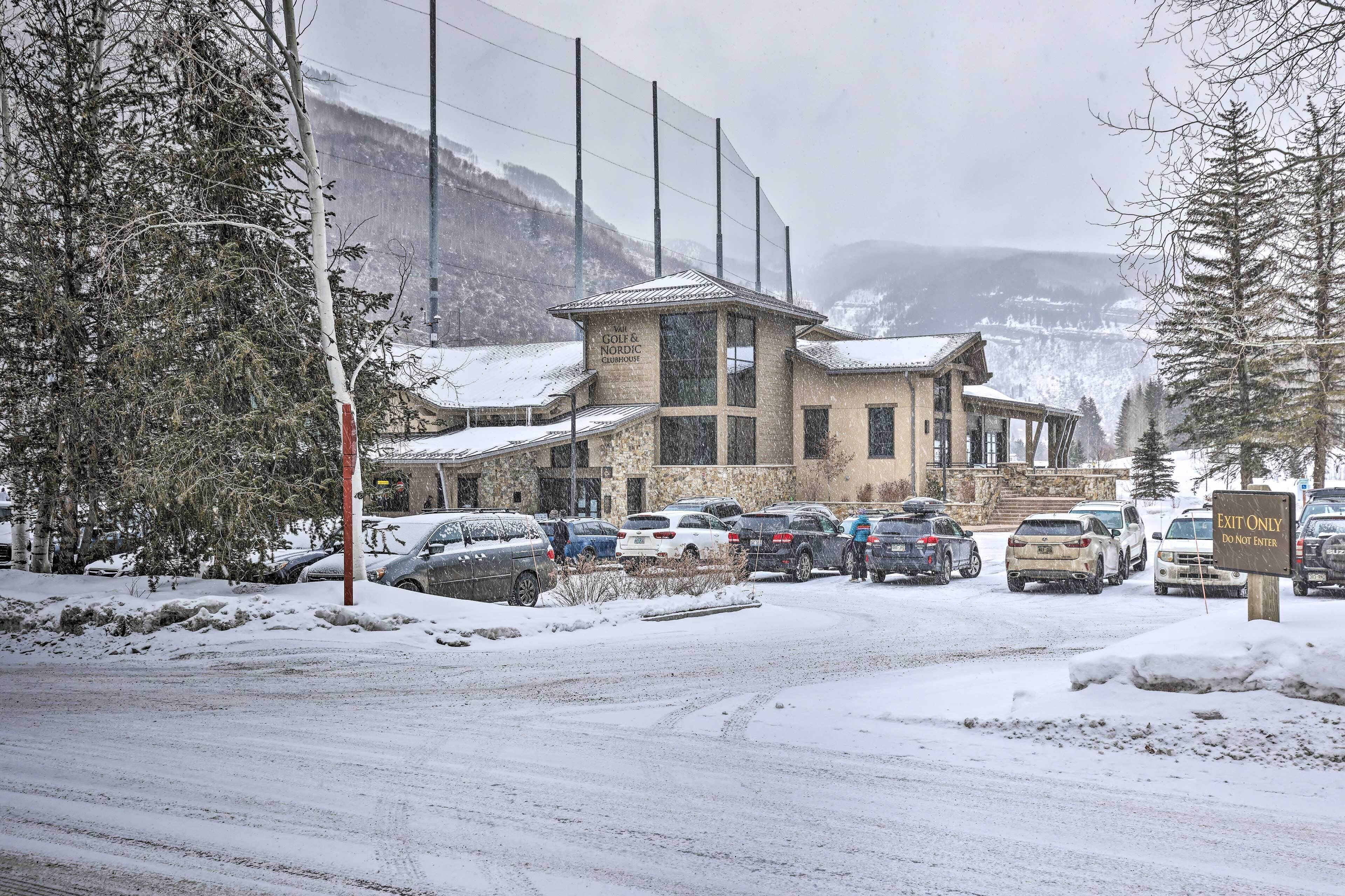 Un edificio con fachada de piedra y varias ventanas, rodeado de coches aparcados y suelo cubierto de nieve.