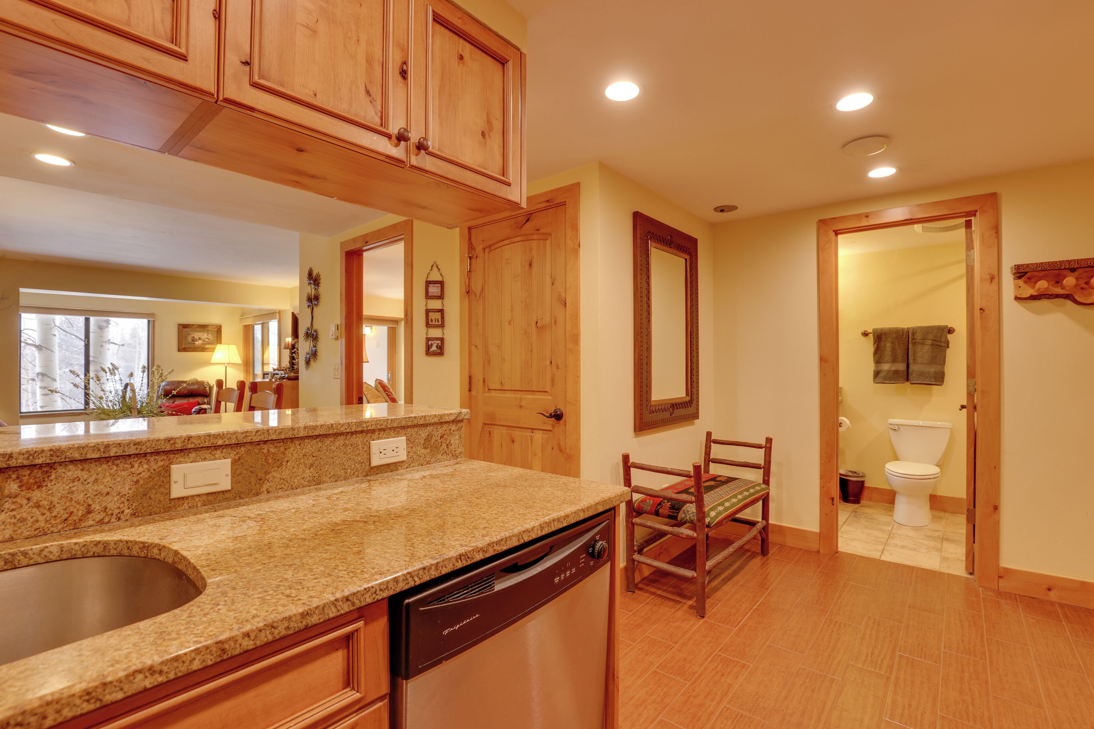 A kitchen with wooden cabinets, a built-in dishwasher, and a granite countertop.
