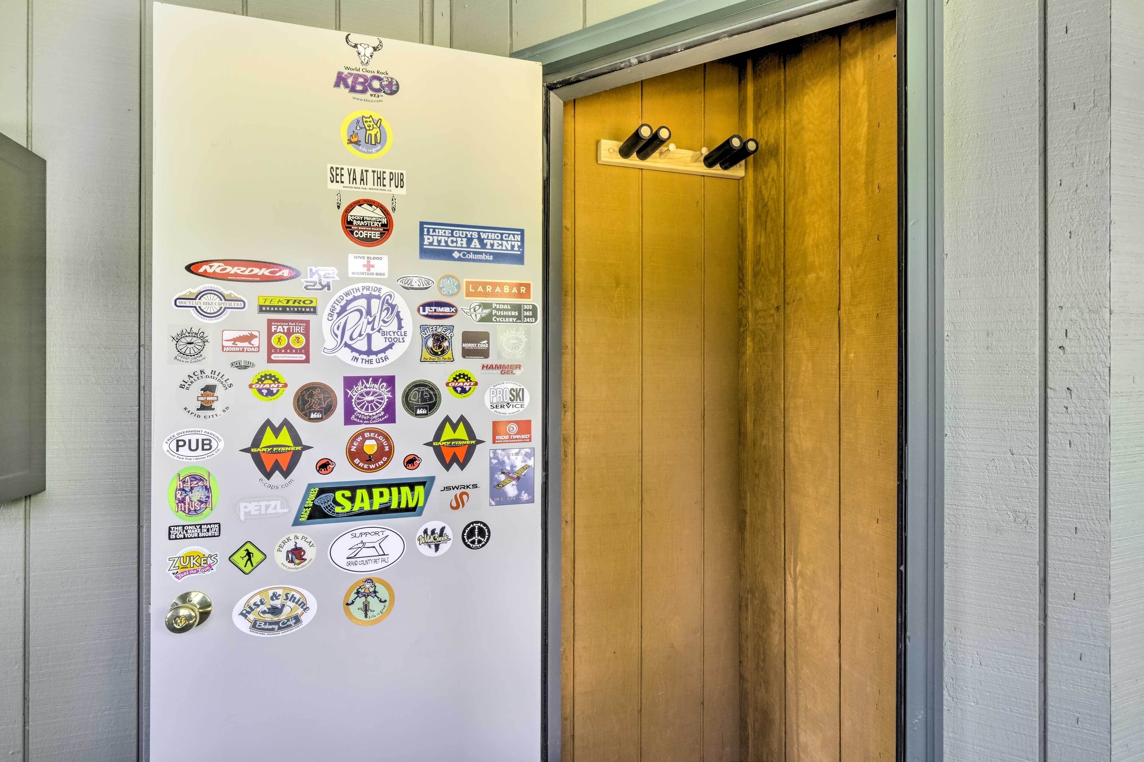 Uma porta com superfície branca coberta por diversos adesivos e moldura de madeira.