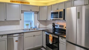 A kitchen with grey cabinets, stainless steel appliances, a microwave, and a dishwasher. - Location! Outdoor Living Hot Tub Walkable Denver (Edgewater)