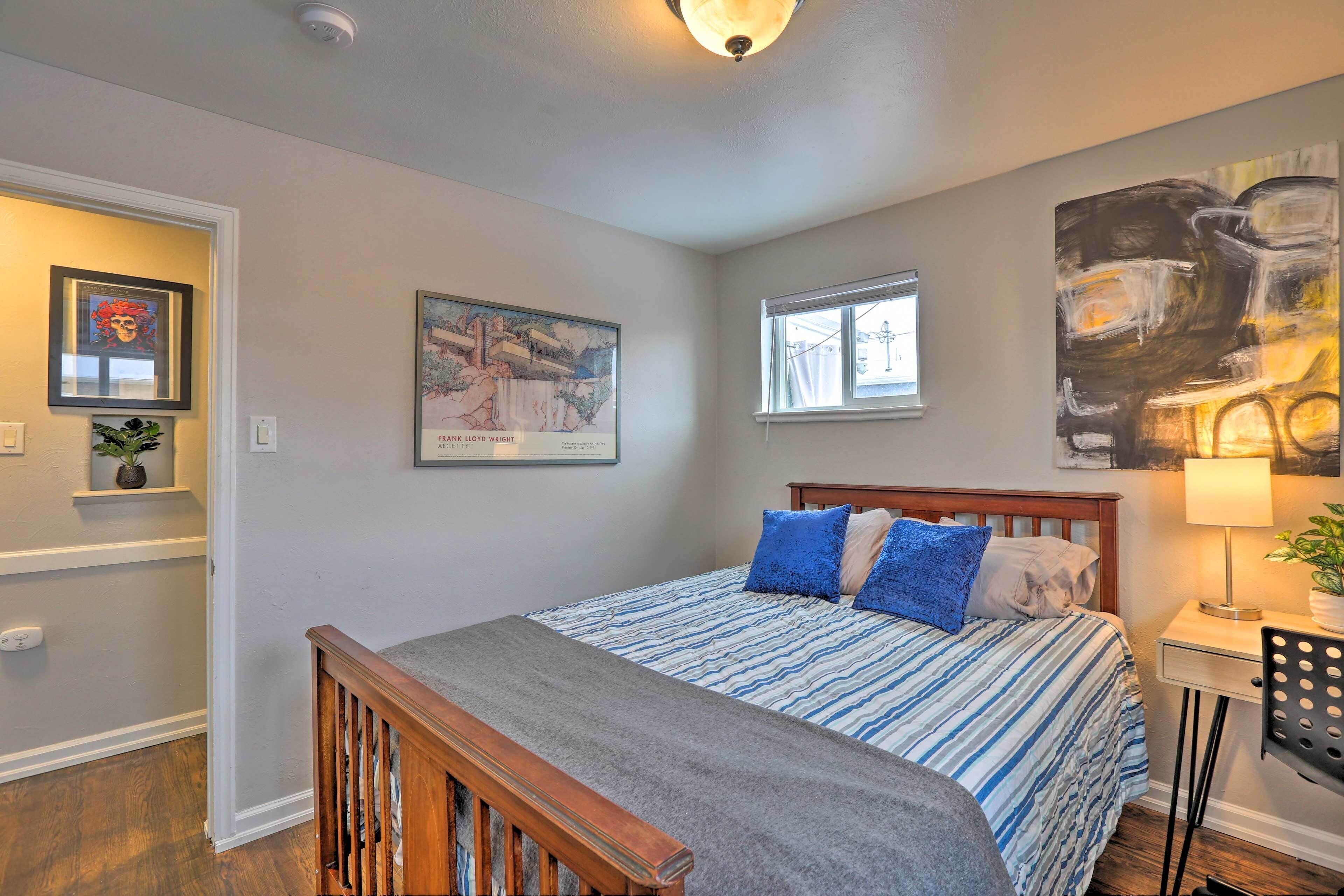 A bedroom with a bed, a nightstand, a lamp, and a window.
