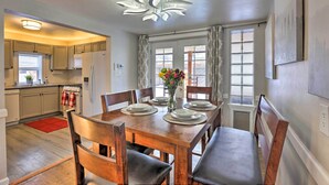 A dining area with a wooden table set for four, a vase with flowers, and a view of the kitchen in the background. - Location! Outdoor Living Hot Tub Walkable Denver (Edgewater)