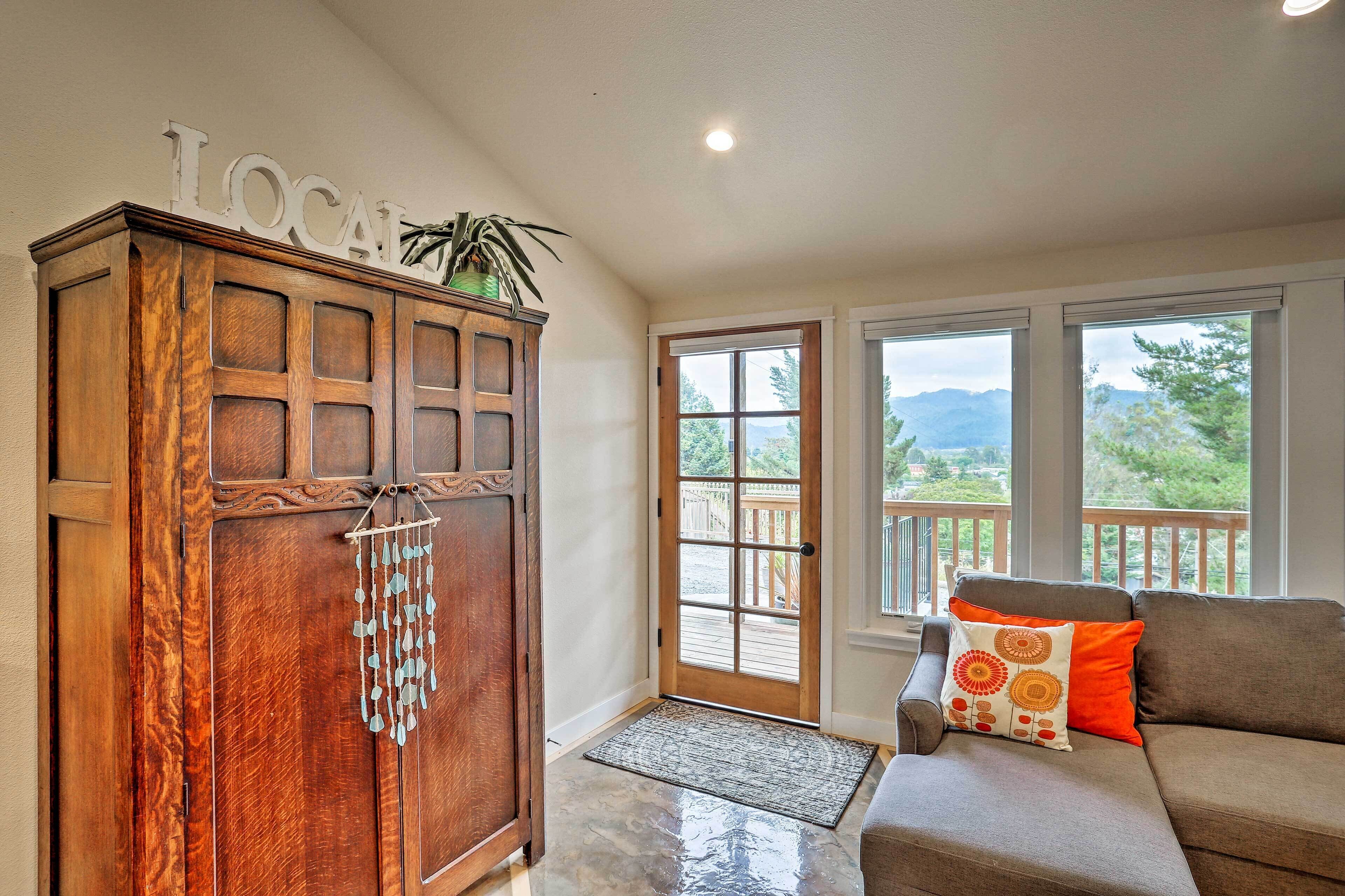 A wooden cabinet with a 'LOCAL' sign, a door with a view of the outdoors, and a gray sofa with patterned cushions.