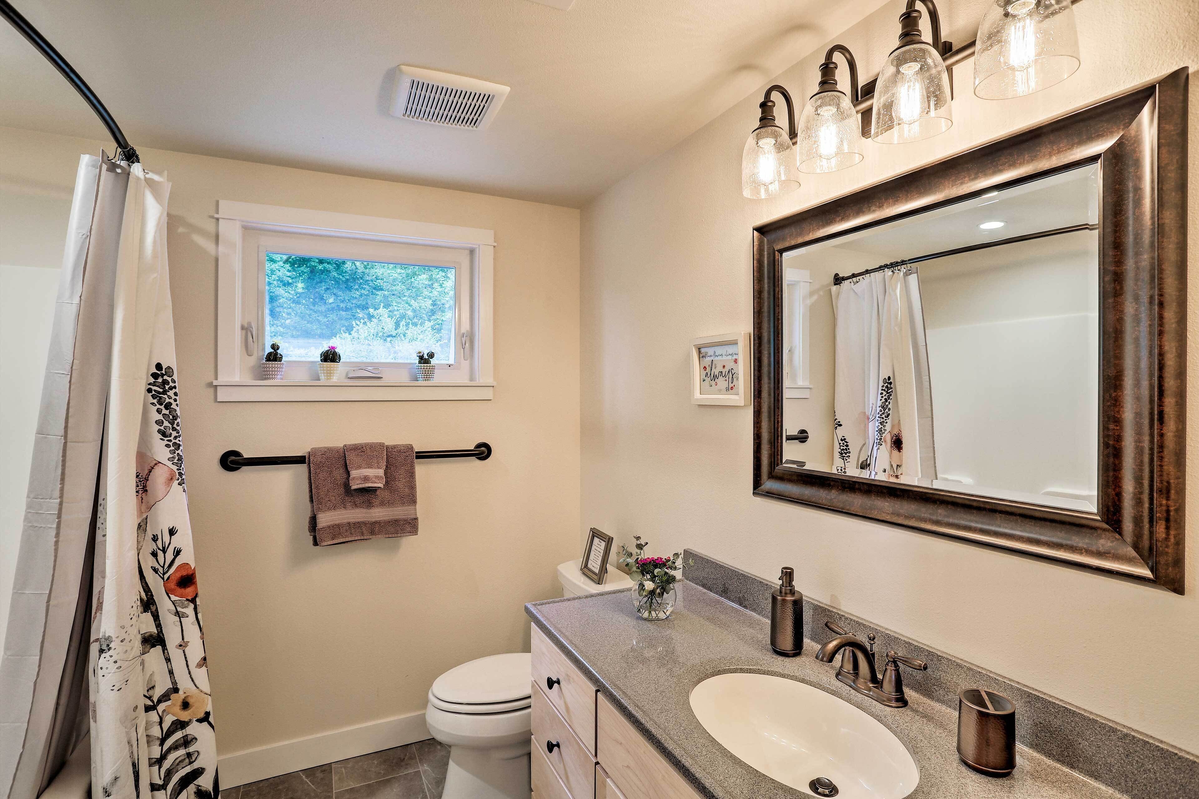 Un baño con un espejo grande, un lavabo, un inodoro y una ventana.