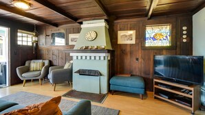 Ein gemütliches Wohnzimmer mit Kamin, bequemen Sitzmöglichkeiten, einem Fernseher und Holzwänden.