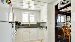 Eine Küche mit weißen Schränken, einem Kühlschrank, einer Mikrowelle und einem Fenster.