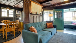 Ein gemütliches Zimmer mit einem grünen Sofa, einem Holzesstisch und Stühlen.