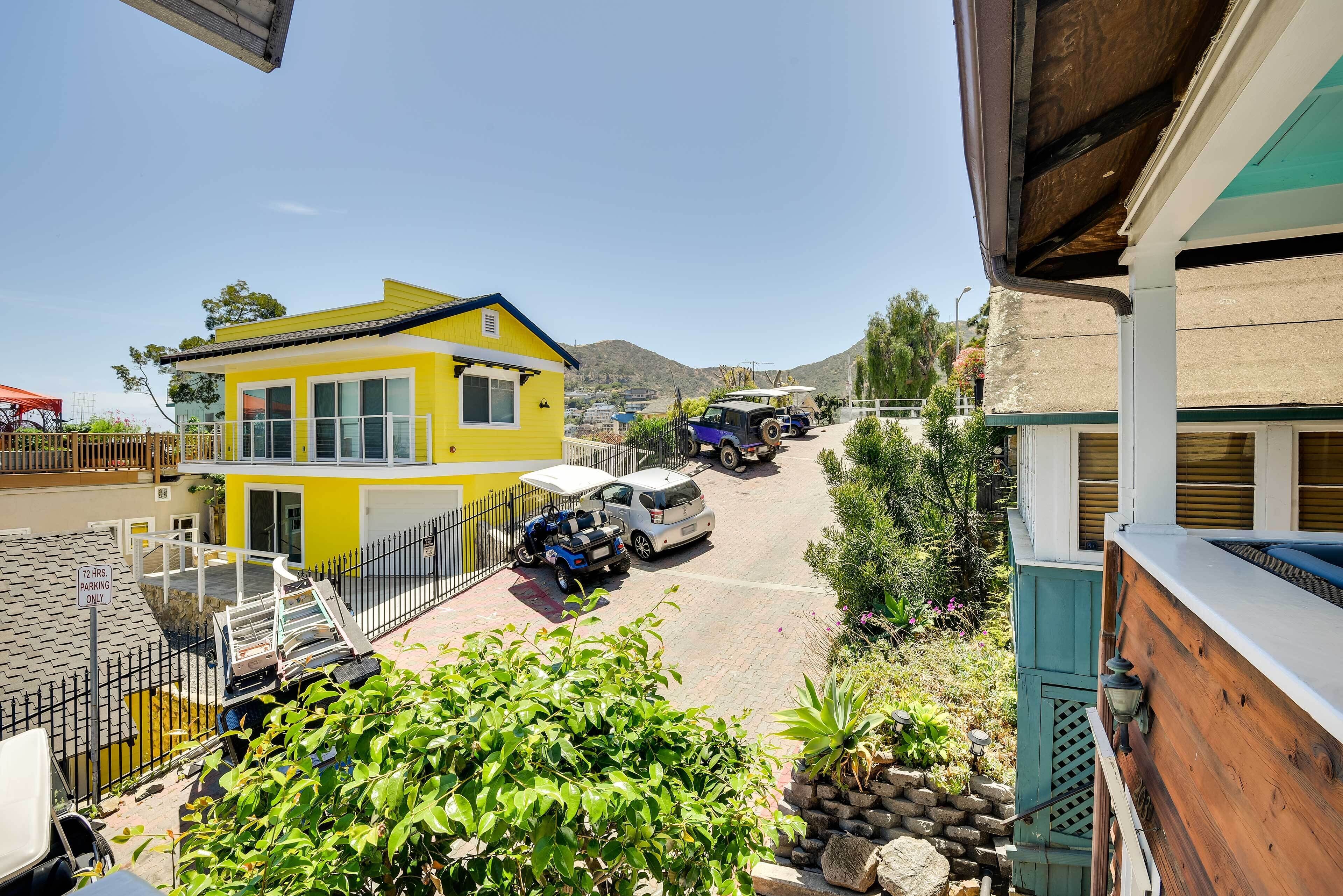 A yellow building with a white roof, a parked car, and a blue vehicle.
