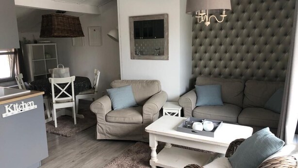 Ett modernt vardagsrum med ett köksområde, inrett med en soffa, ett soffbord och ett matbord.
