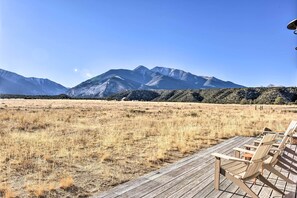 A wooden deck with chairs overlooking a dry grass field and mountains in the background. - Nathrop Getaway w/ Collegiate Peak Views! (Nathrop)