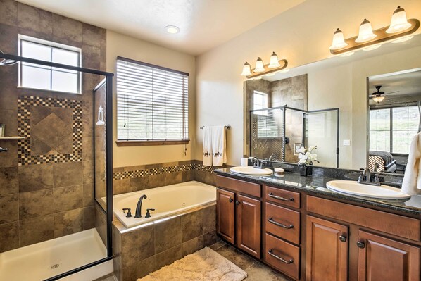 Un baño moderno con una bañera grande, dos lavabos, armarios de madera y un espejo amplio.
