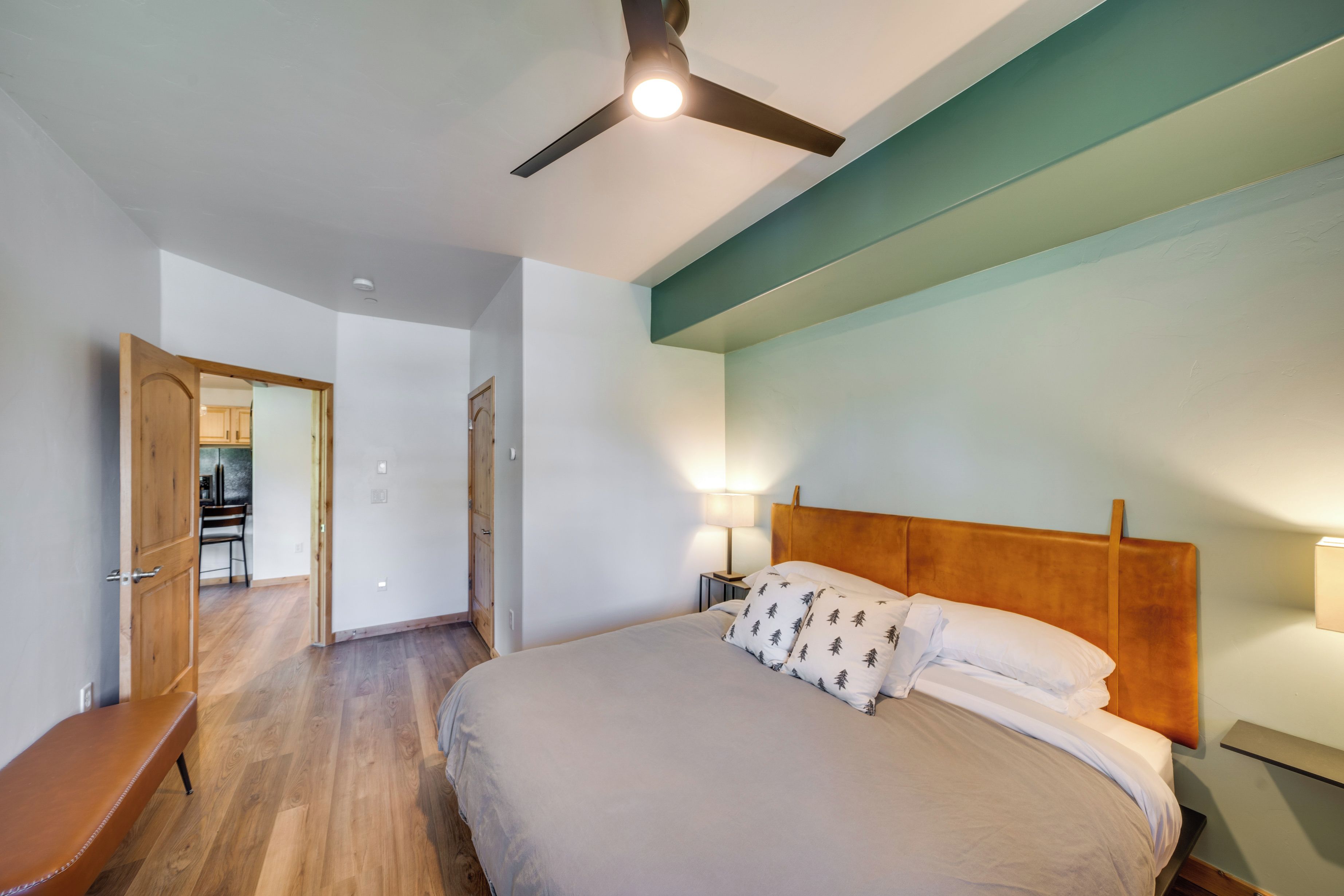 Ein Schlafzimmer mit Bett, Nachttischlampen, Deckenventilator und einer Holzbank.