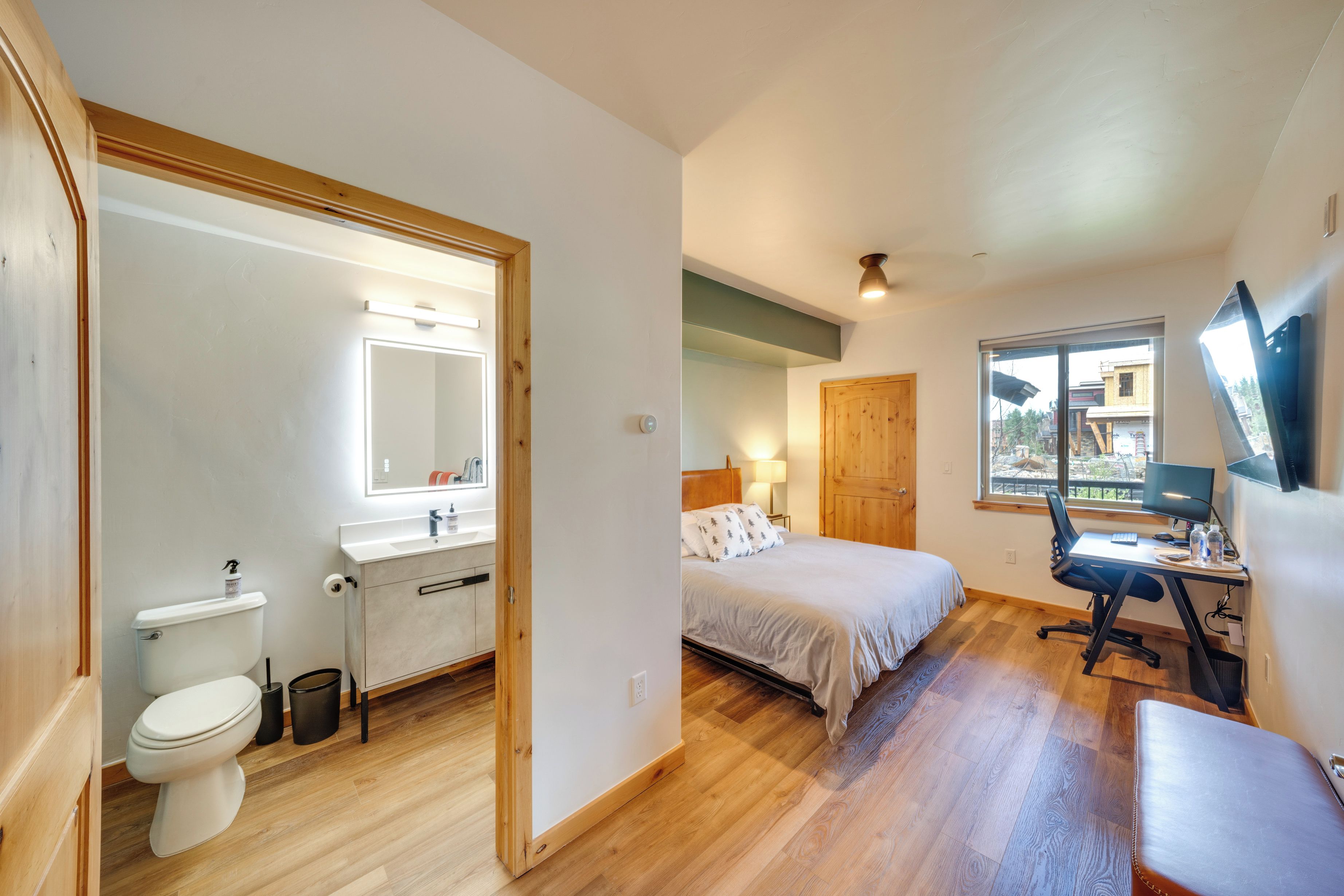 A bedroom with a bed, a desk, and a window.