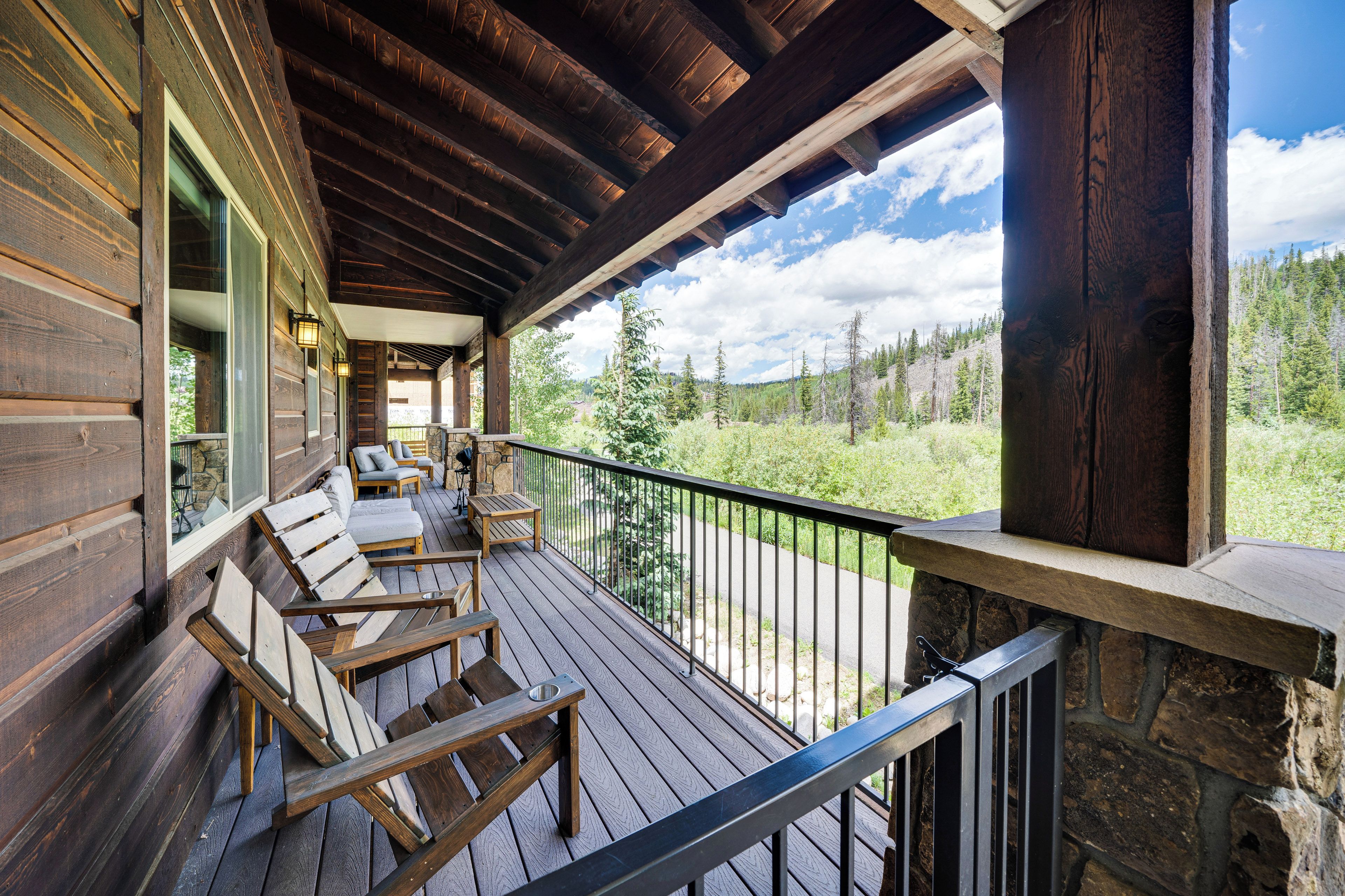 A wooden deck with outdoor seating and a stone wall.