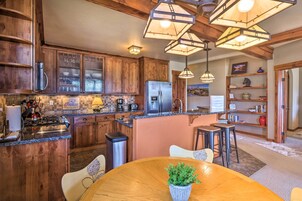 Una cocina con armarios de madera, un refrigerador de acero inoxidable y una zona de comedor con mesa y sillas de madera.