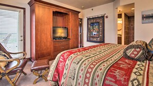 Une chambre à coucher avec un grand lit, une armoire en bois, une télévision et une tapisserie décorative.