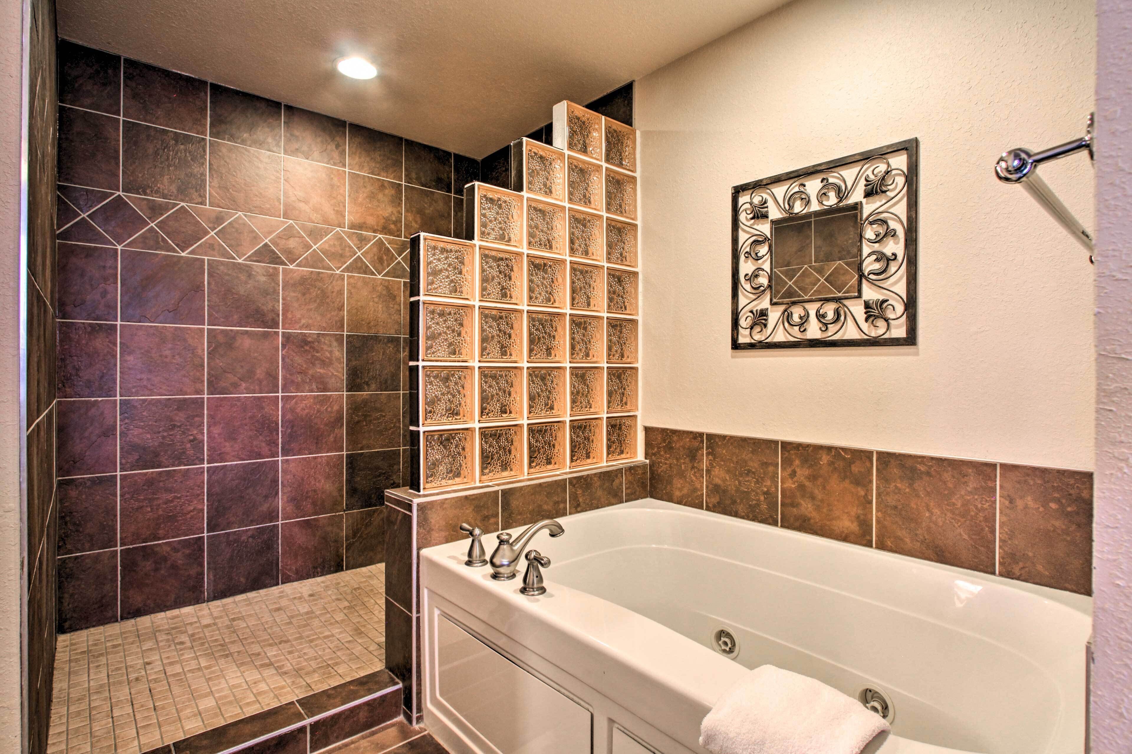 A bathroom with a bathtub, a shower area, and a decorative wall panel.