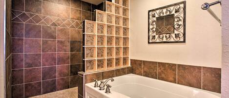 A bathroom with a bathtub, a shower area, and a decorative wall panel.
