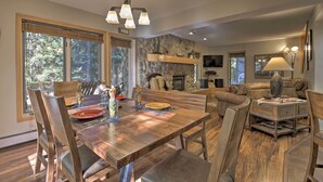 A dining area with a wooden table, chairs, and a stone wall. - Creekside Frisco Condo w/ Views & Pool Access! (Frisco)
