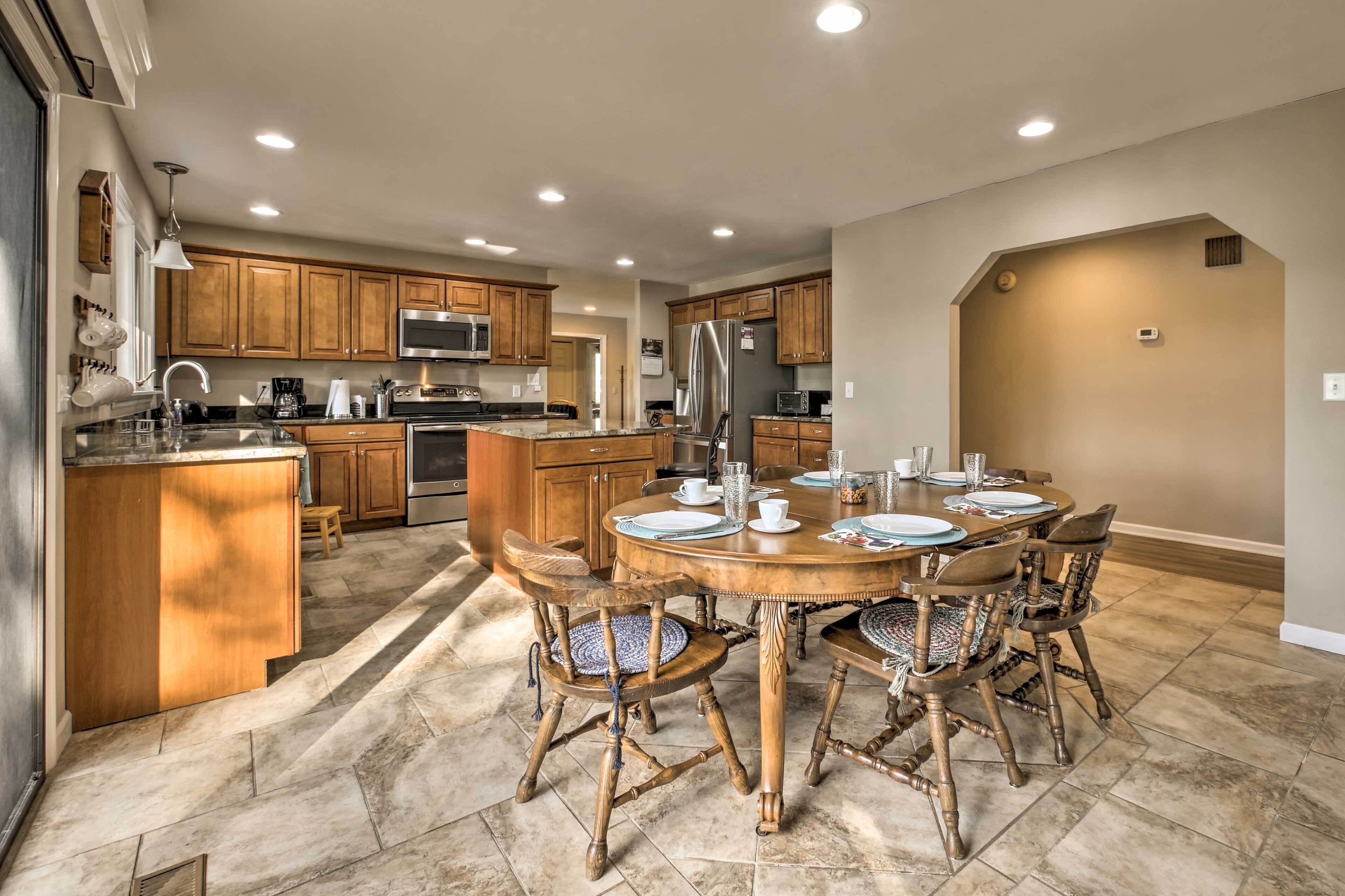 A spacious kitchen with wooden cabinets, a central island, and a dining area with a round table and chairs.