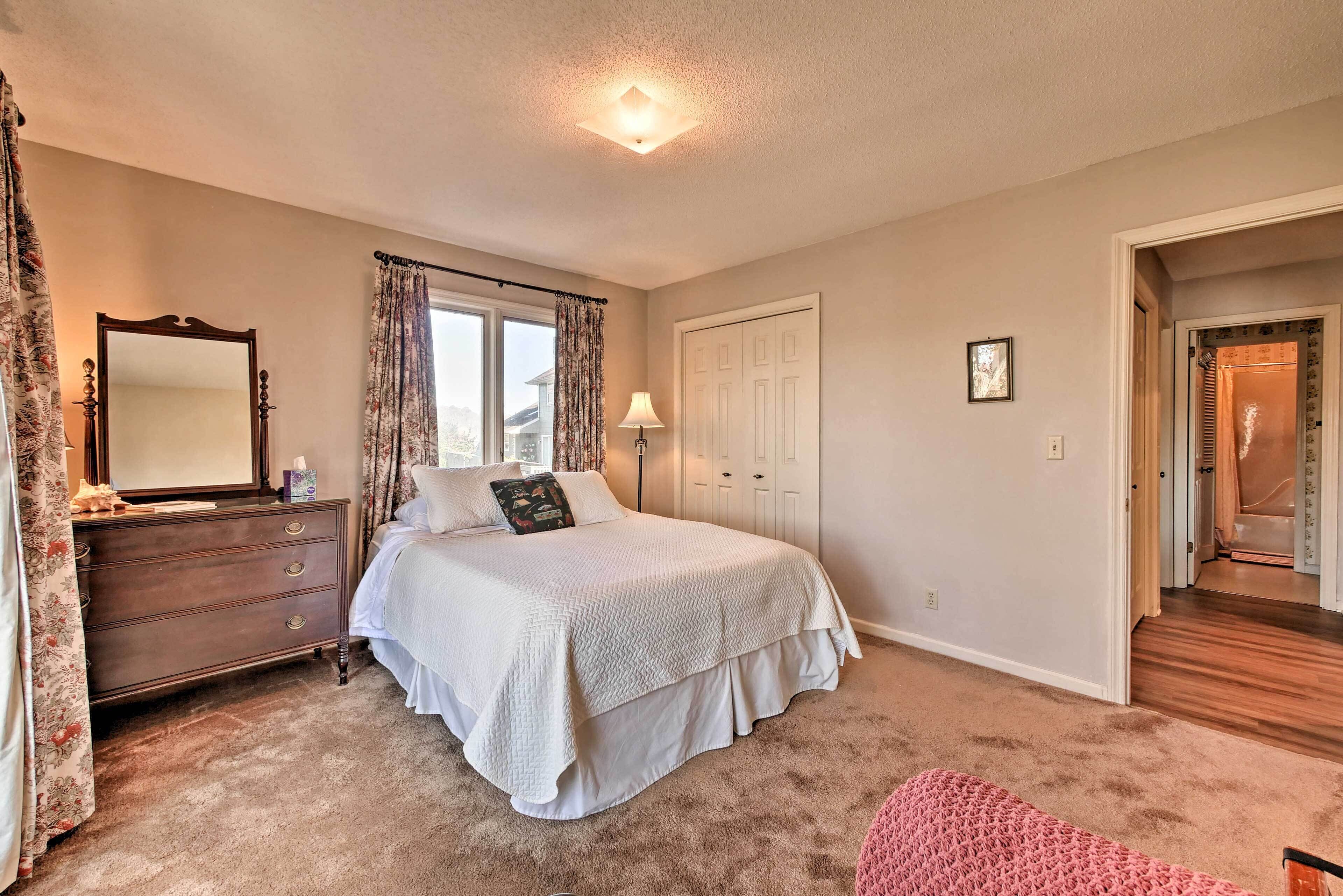 Une chambre à coucher comprenant un lit, une commode, un miroir et une porte donnant sur une autre pièce.