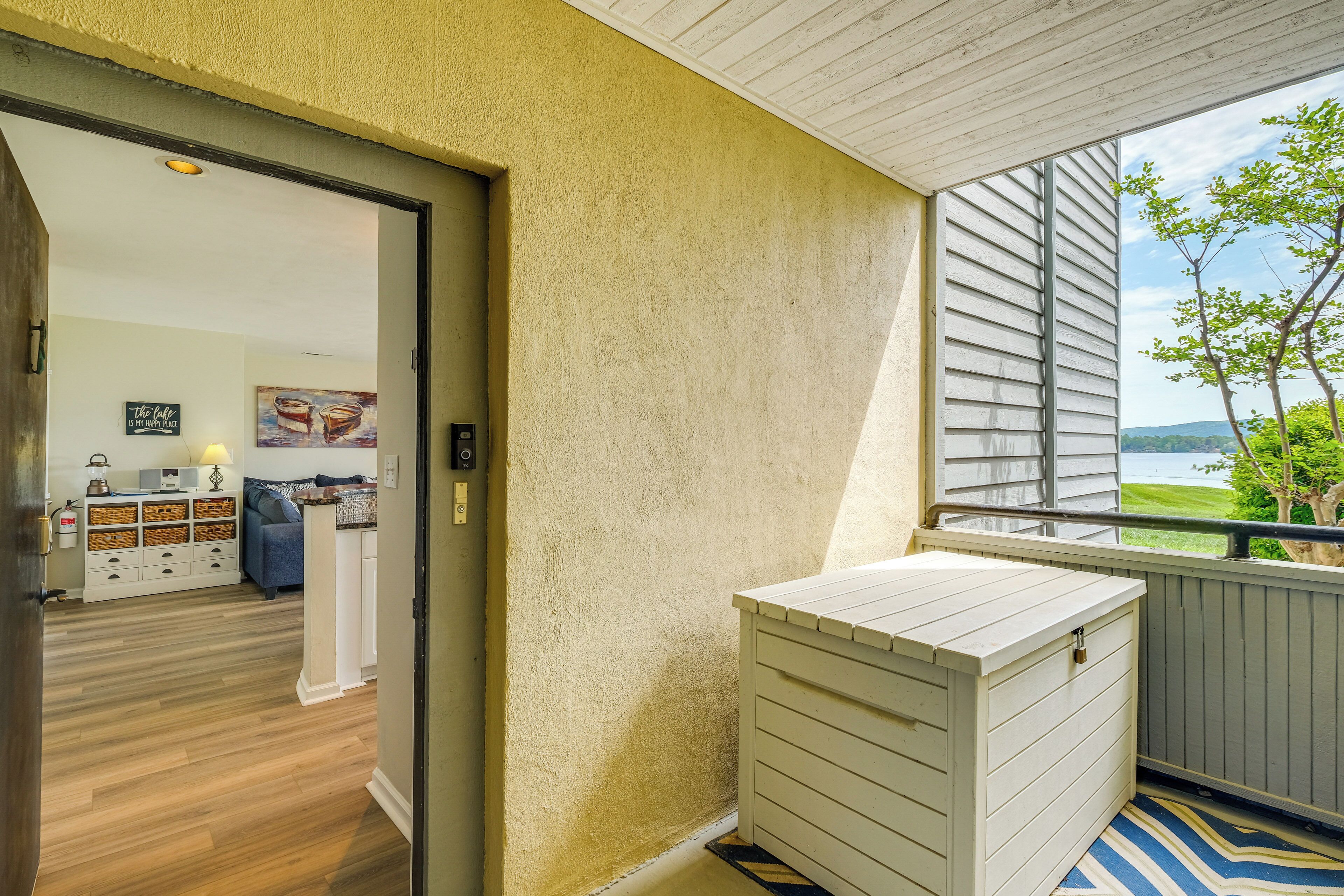 A room with a wooden floor, a white cabinet, a painting, and a view of a lake.