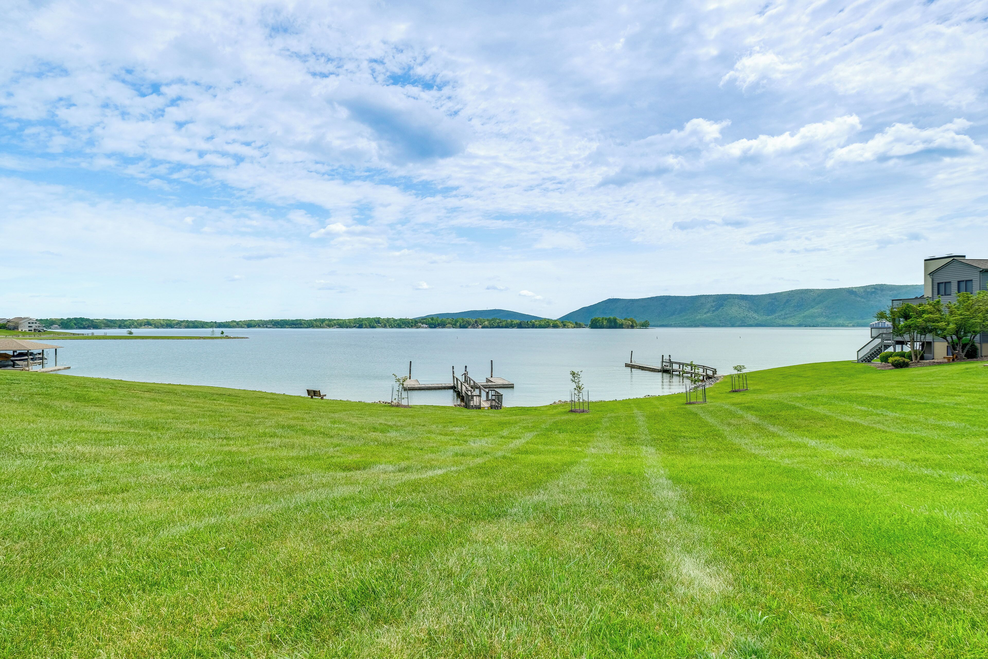 A grassy area with a dock and a house by a lake.