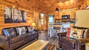 Ein gemütliches Blockhaus-Interieur mit Holzvertäfelung, einem Essbereich und einer Küche mit Kühlschrank und Mikrowelle.