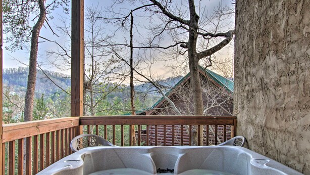Ein Whirlpool auf einer Holzterrasse mit Blick auf Bäume und Berge.