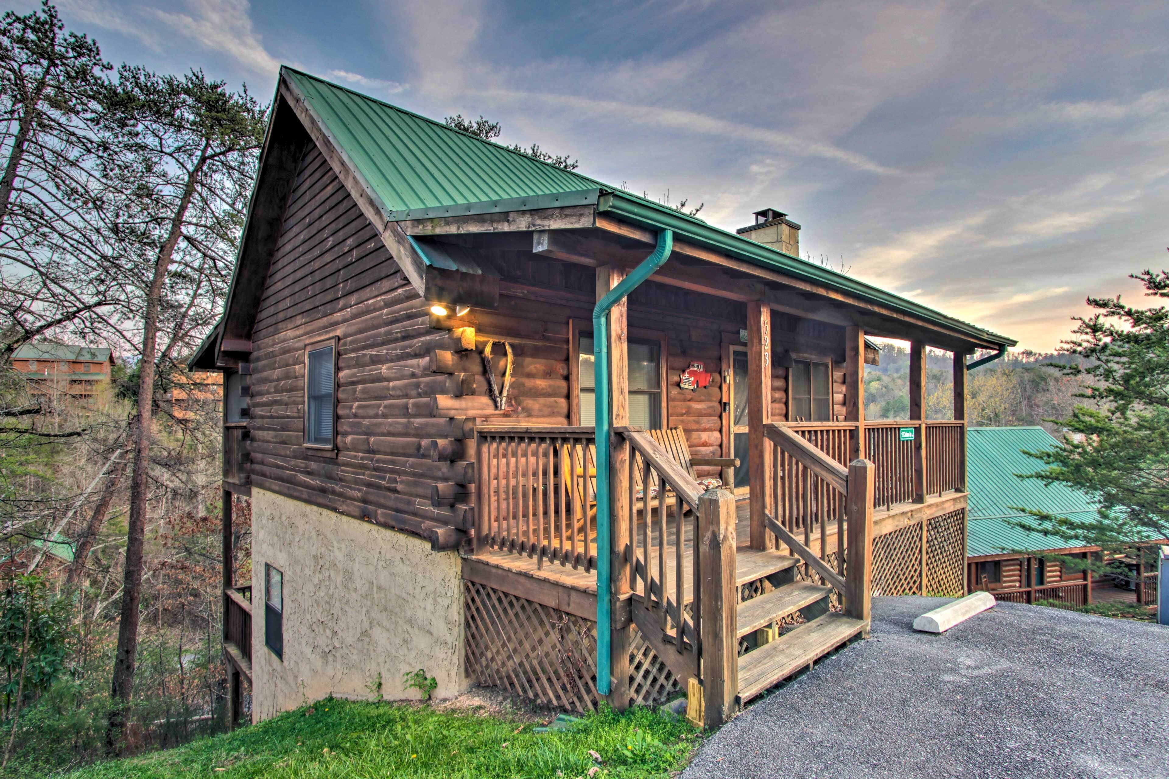 Eine rustikale Blockhütte mit Veranda, Treppe und einem grünen Dach.