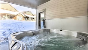 A hot tub with a view of a building and snow outside.