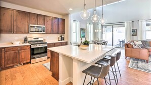 A modern kitchen with wooden cabinets, stainless steel appliances, and a large island with bar stools.