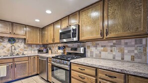 A kitchen with wooden cabinets, stainless steel appliances, and a tiled backsplash. - Pagosa Springs Townhome w/ Mountain Views! (Pagosa Springs)