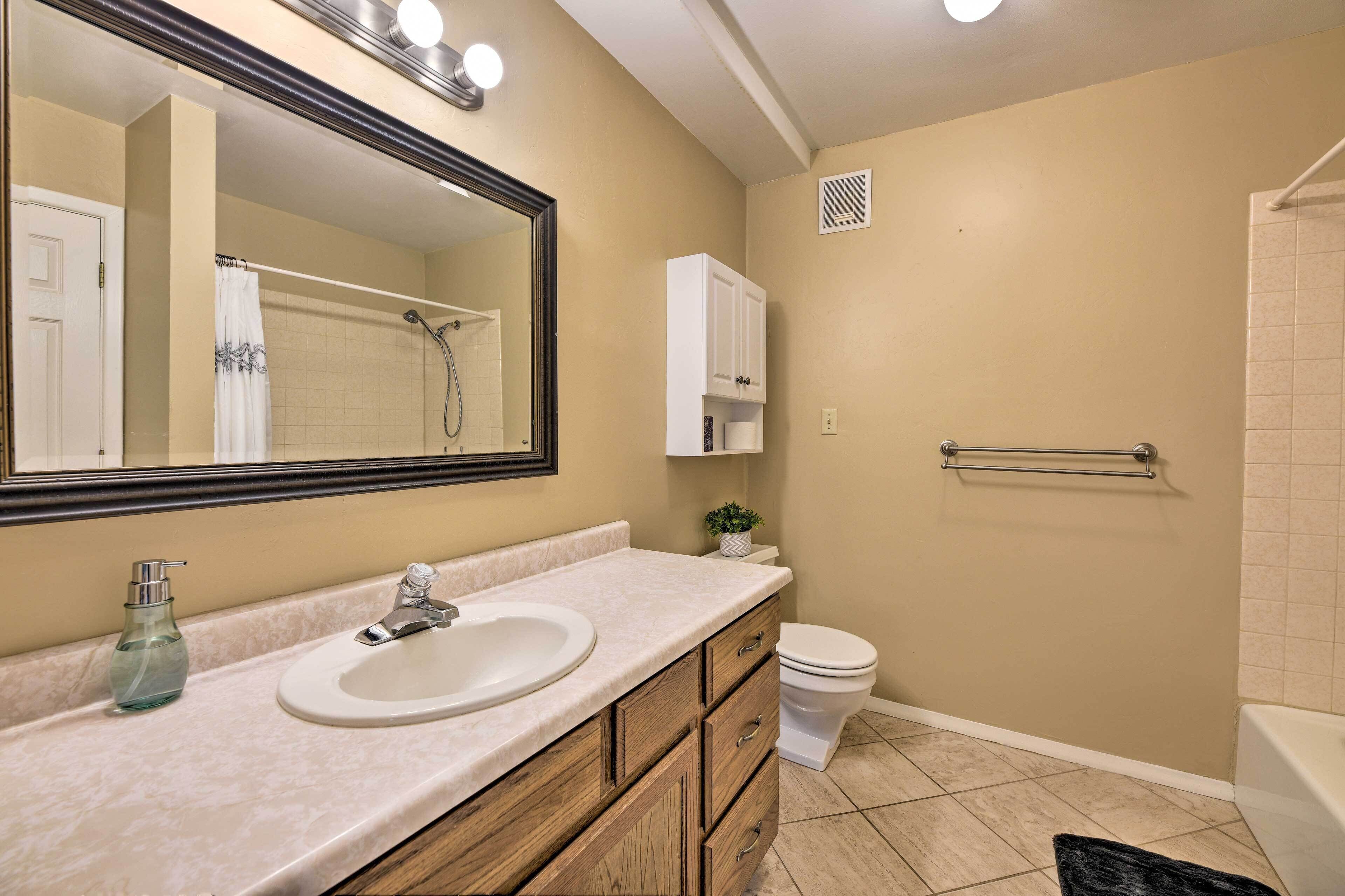 A bathroom with a sink, mirror, cabinet, toilet, and shower.