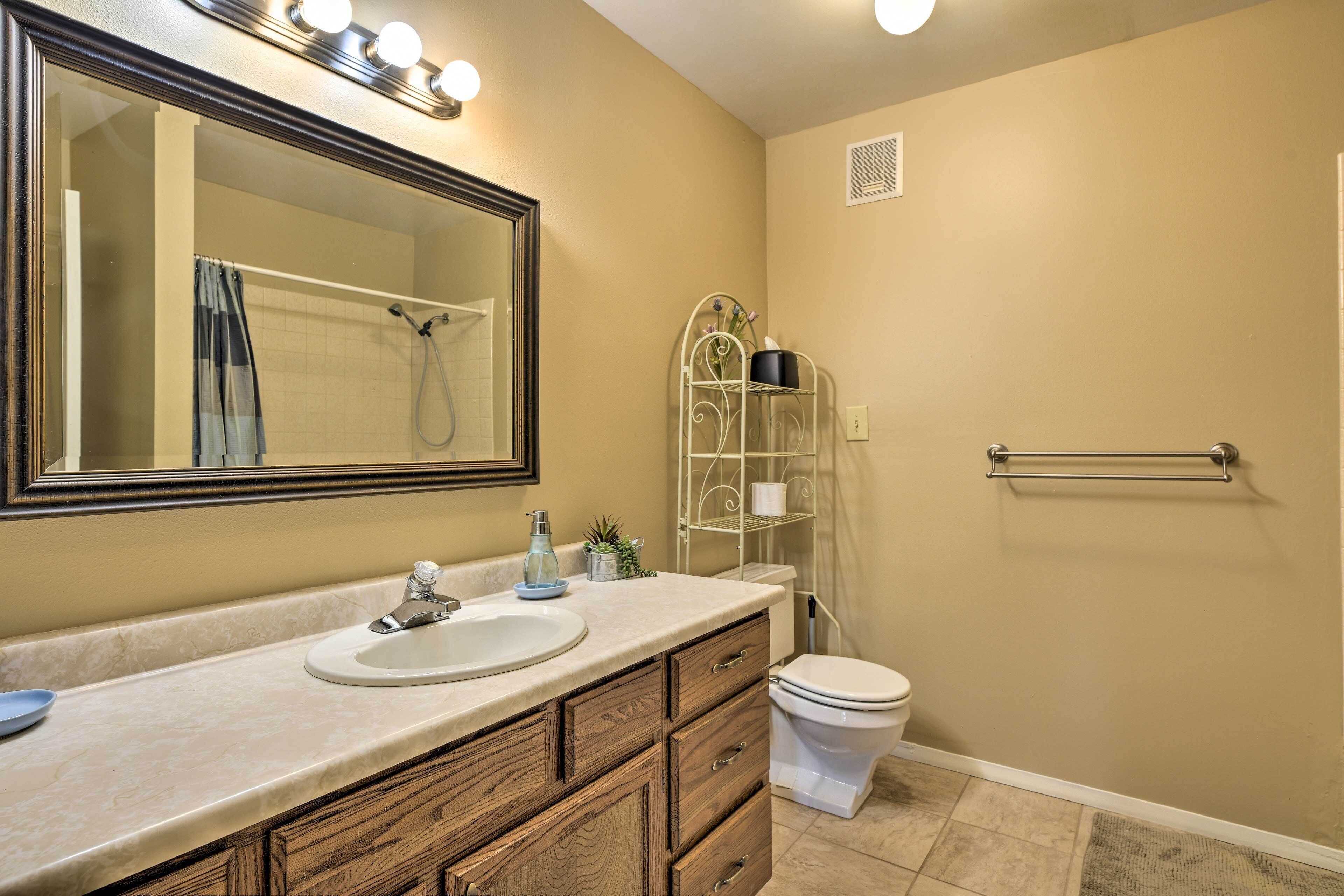 A bathroom with a vanity, sink, mirror, and toilet.