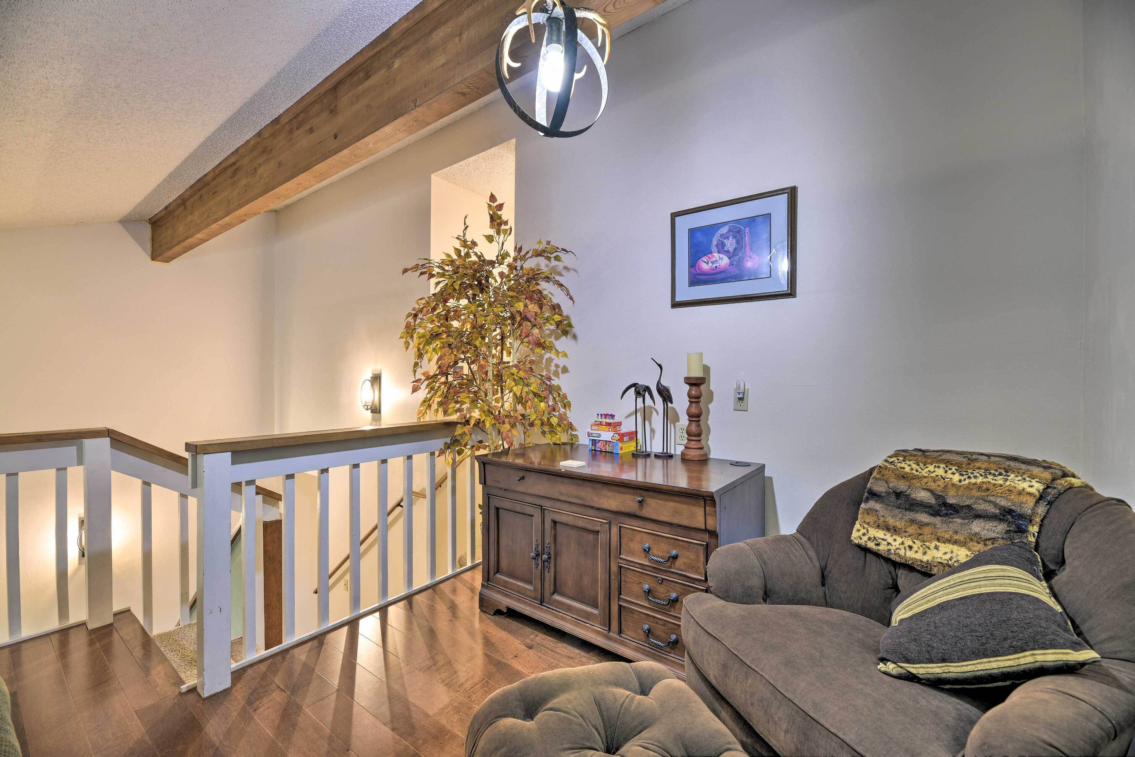 A living room with a wooden staircase, a sofa, a cabinet, and a potted plant.