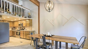A modern kitchen with wooden cabinets, a dining table with chairs, and a chandelier. - Pagosa Springs Townhome w/ Mountain Views! (Pagosa Springs)