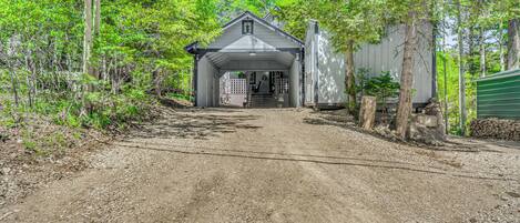 A rustic cabin with a dirt driveway leading to a covered entrance.