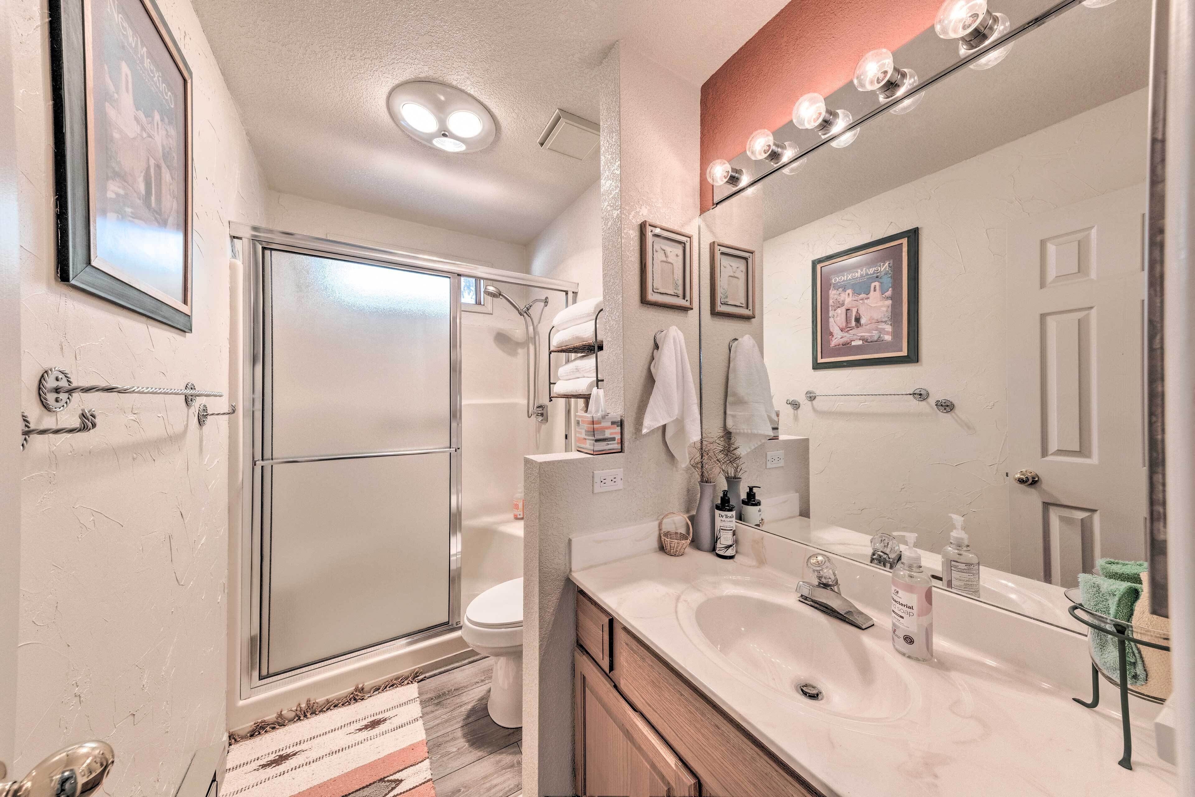 A bathroom with a shower, toilet, and a vanity with a sink and mirror.