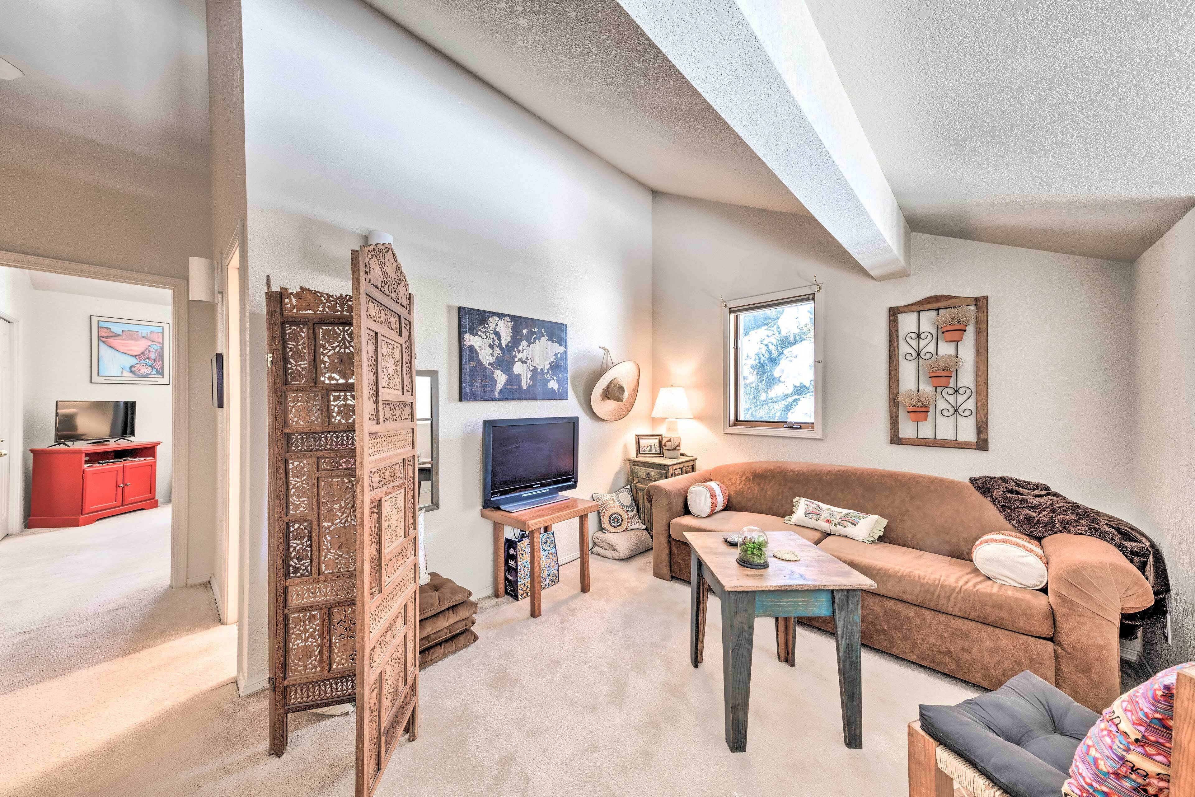 A cozy living room with a brown sofa, a wooden coffee table, a TV, and decorative items.