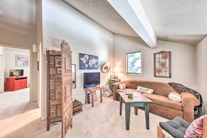 A cozy living room with a brown sofa, a wooden coffee table, a TV, and decorative items.
