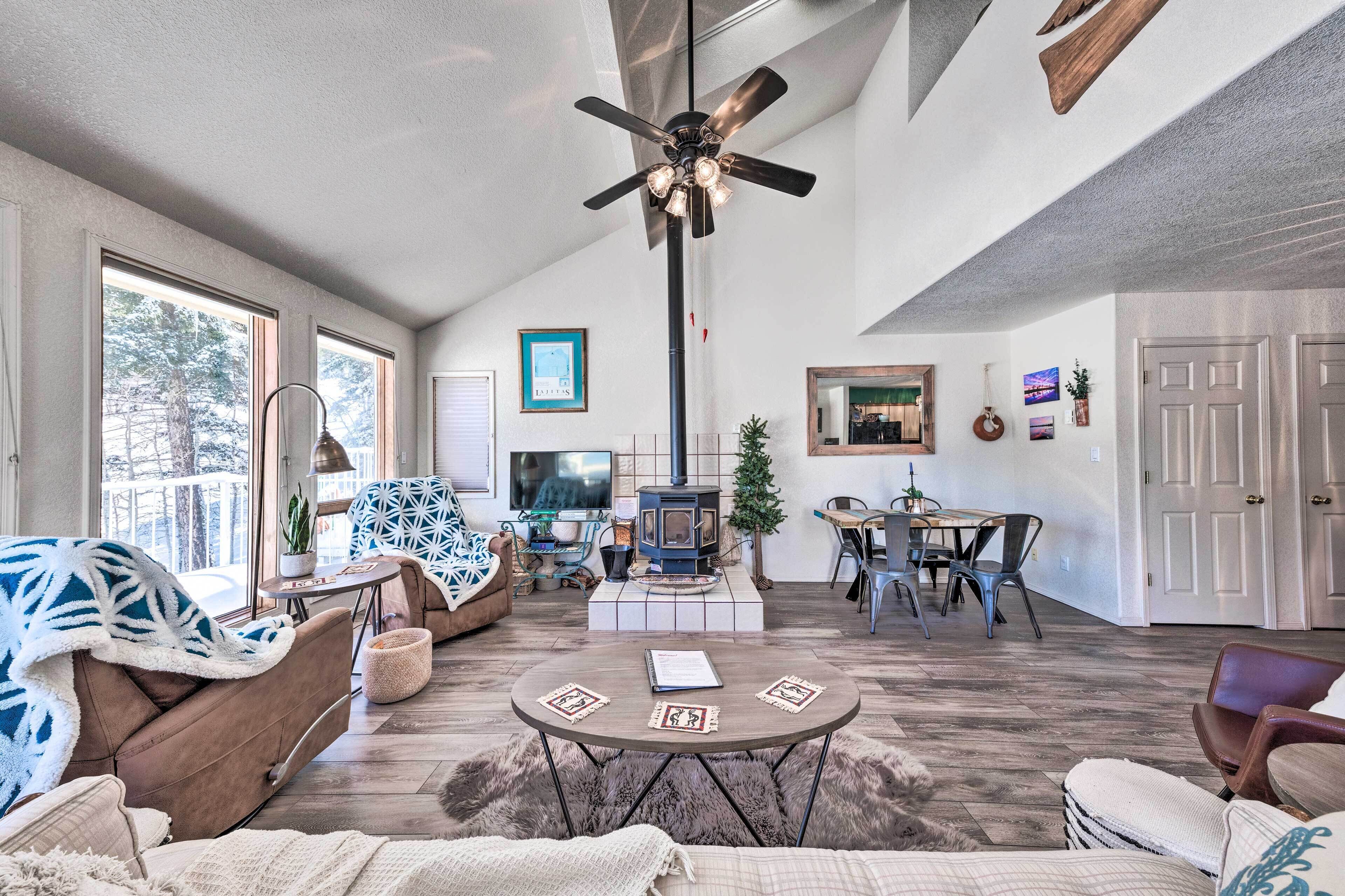 A spacious living room with a fireplace, a ceiling fan, and a dining area.