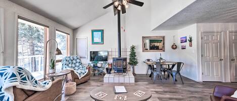 A spacious living room with a fireplace, a ceiling fan, and a dining area.