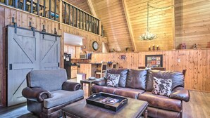 A rustic interior with a loft area, wooden walls, a leather sofa set, and a dining area. - Ski-in/ski-out Red River Cabin w/ Mtn Views! (Red River)