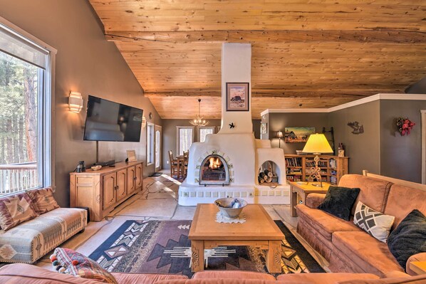 Een gezellige woonkamer met een open haard, houten plafond en comfortabele zitplaatsen.