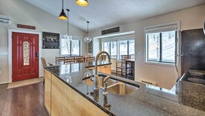 A kitchen with a granite countertop, stainless steel sink, pendant lights, and a red door. - Bright Wintergreen Resort Home; Deck & Grill! (Roseland)