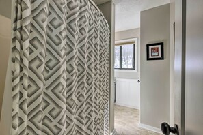 A hallway with a geometric patterned curtain, a door with a black handle, and a framed picture on the wall. - Bright Wintergreen Resort Home; Deck & Grill! (Roseland)